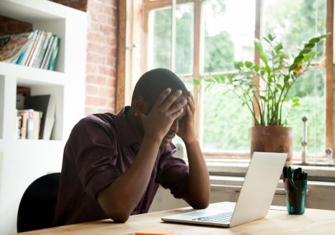 Man met handen in het haar voor laptop